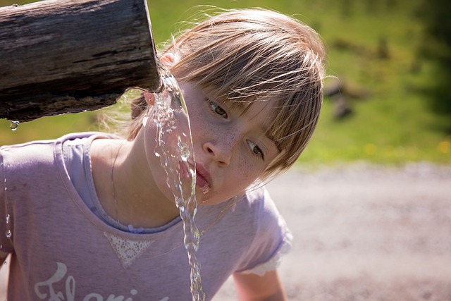 una ragazza che beve l'acqua dal sorgente