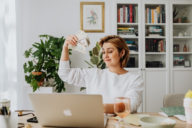 Come chiedere un aumento? Donna sorridente con soldi in mano